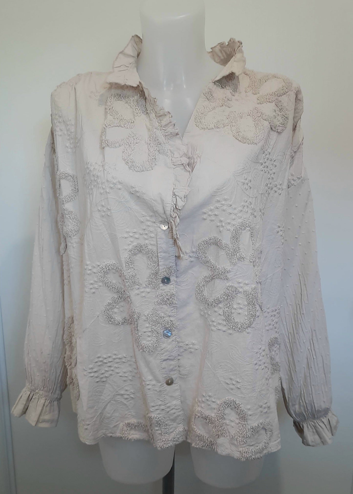 Blouse romantique beige pour femme avec broderies florales en relief et col à volants – manches longues bouffantes et fermeture boutonnée, parfaite pour un look chic et bohème.