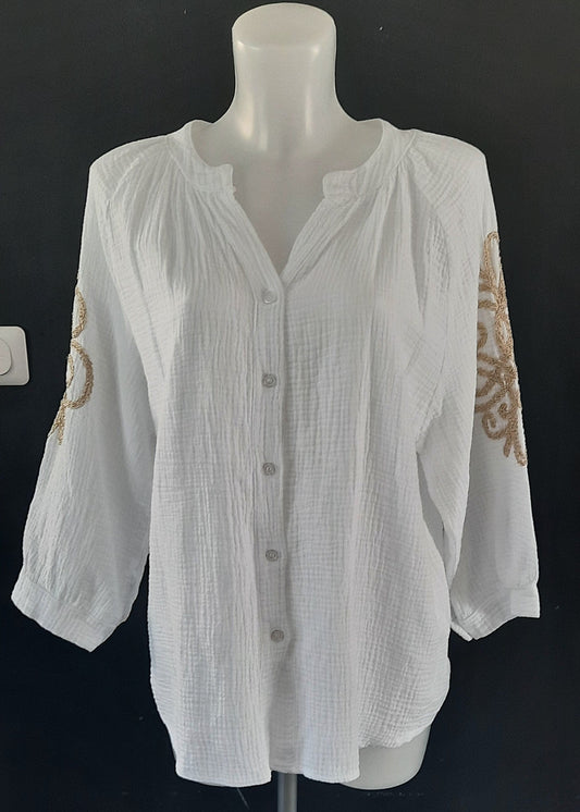 Blouse blanche en gaze de coton pour femme, manches 3/4 avec broderies dorées sur les bras, encolure tunisienne et boutonnage frontal. Style bohème chic et léger.