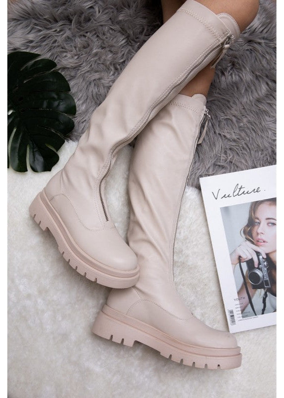 Bottes beiges pour femme en simili cuir, fermeture zippée à l’avant, semelle plateforme crantée et hauteur au-dessous du genou. Bottes tendance et confortables signées Timalya, parfaites pour un look urbain et moderne.
