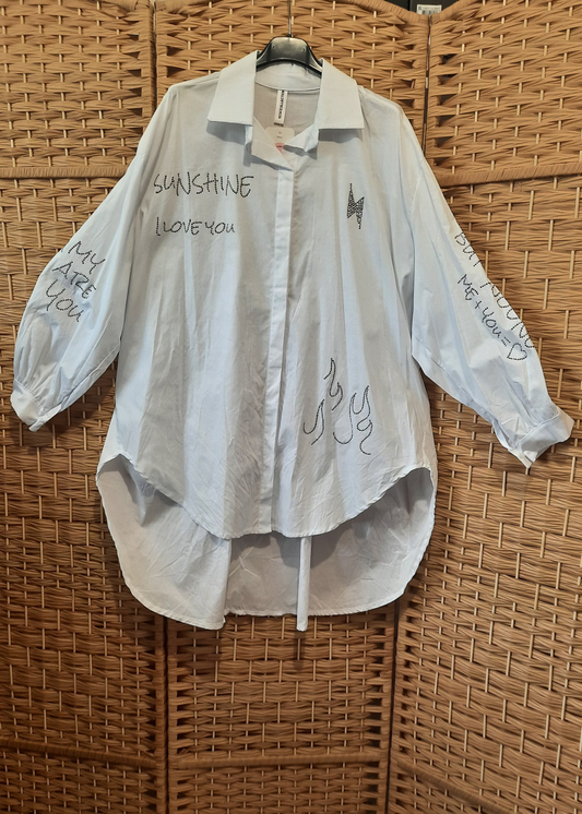 Chemise blanche oversize femme avec inscriptions en strass – design asymétrique et moderne, manches longues bouffantes, idéale pour un look casual chic.