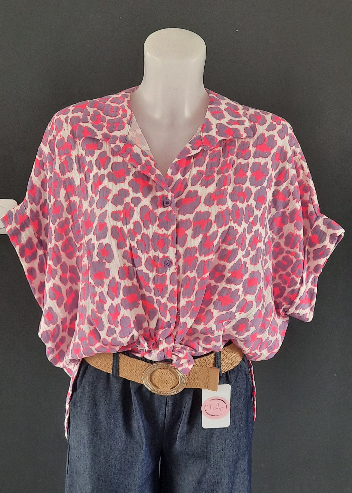 Chemise fluide à manches courtes pour femme, imprimé léopard rose et violet sur fond blanc, col classique, nouée à la taille pour un look tendance et estival.