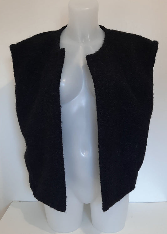 Gilet sans manches en maille duveteuse noir, coupe ample et ouverte sans fermeture, 2 poches. Parfait pour une superposition cosy et stylée en mi-saison.