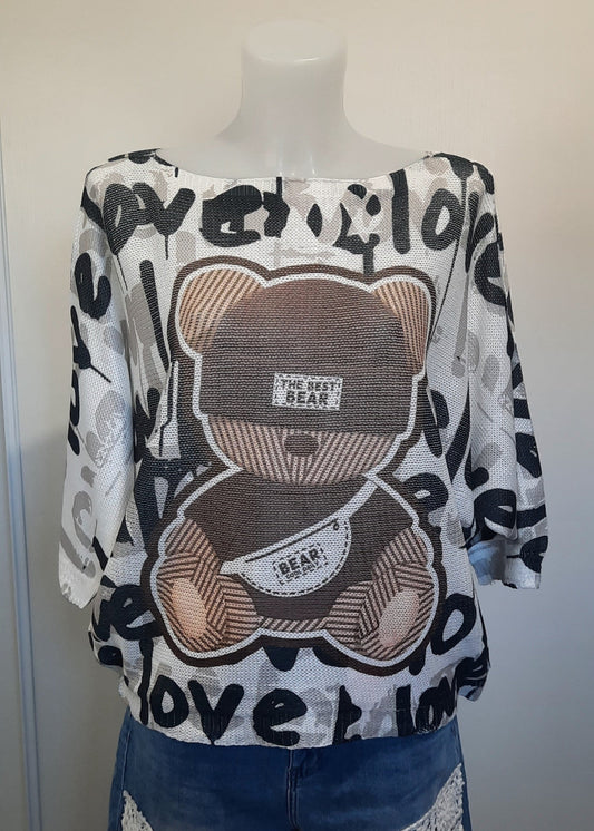 Haut ample blanc à manches 3/4 avec motif nounours marron et inscriptions 'love' en noir, tissu effet mesh léger. Style streetwear décontracté et fun.