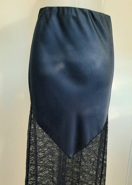Jupe longue bleu marine en satin avec empiècement asymétrique en dentelle transparente à la base. Coupe droite et élégante, idéale pour une tenue de soirée ou une occasion spéciale.