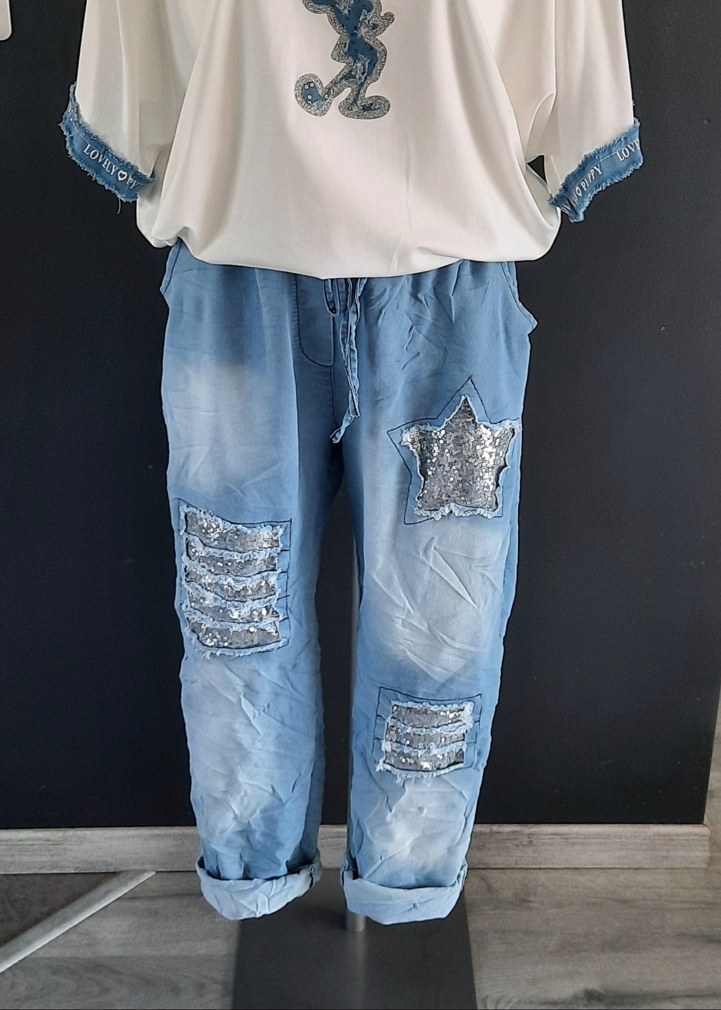 Pantalon jogger bleu clair pour femme, coupe décontractée avec taille élastique et lien à nouer, décoré de patchs à sequins argentés dont une étoile brillante. Style casual tendance avec une touche d’originalité.