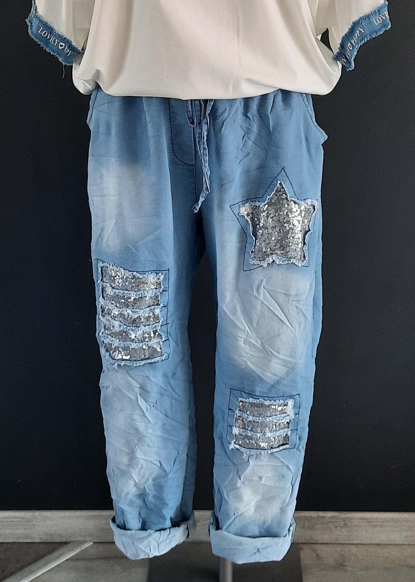 Pantalon jogger bleu clair pour femme, coupe décontractée avec taille élastique et lien à nouer, décoré de patchs à sequins argentés dont une étoile brillante. Style casual tendance avec une touche d’originalité.