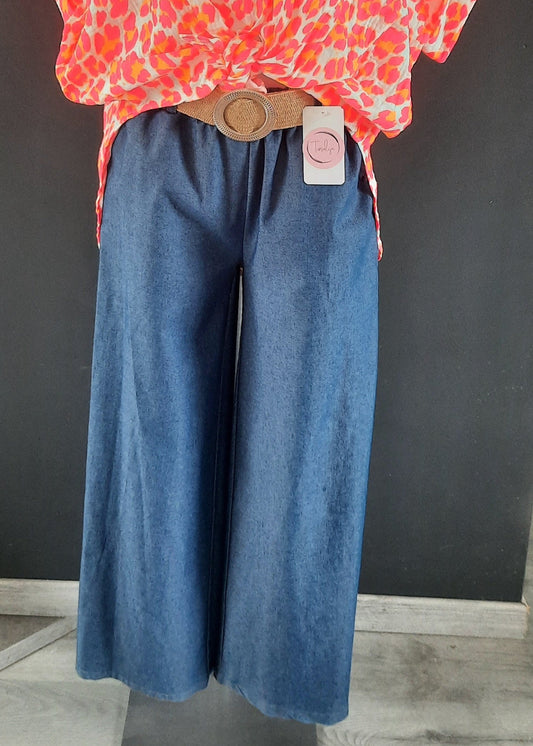 Pantalon large en denim léger clair, coupe fluide style palazzo, ceinture élastique tressée beige avec boucle ronde dorée. Look décontracté chic, parfait pour le printemps et l’été.