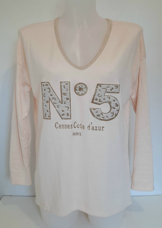 T-shirt beige à manches longues pour femme, col en V avec bord lurex doré, inscription 'N°5 Cannes Côte d’Azur Paris' en relief léopard et doré. Style casual chic inspiré des tendances parisiennes.