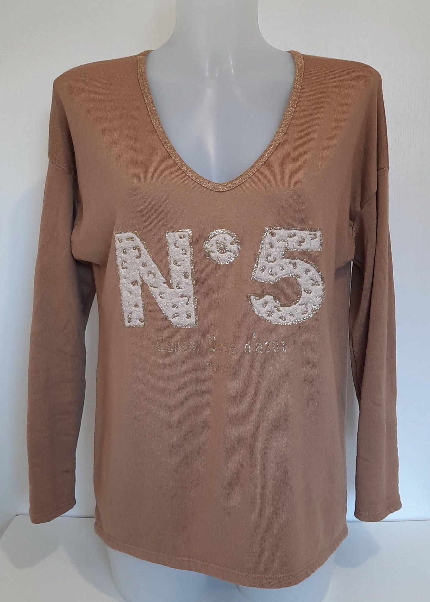 T-shirt camel à manches longues pour femme, col en V avec bord lurex doré, inscription 'N°5 Cannes Côte d’Azur Paris' en relief léopard et doré. Style casual chic inspiré des tendances parisiennes.