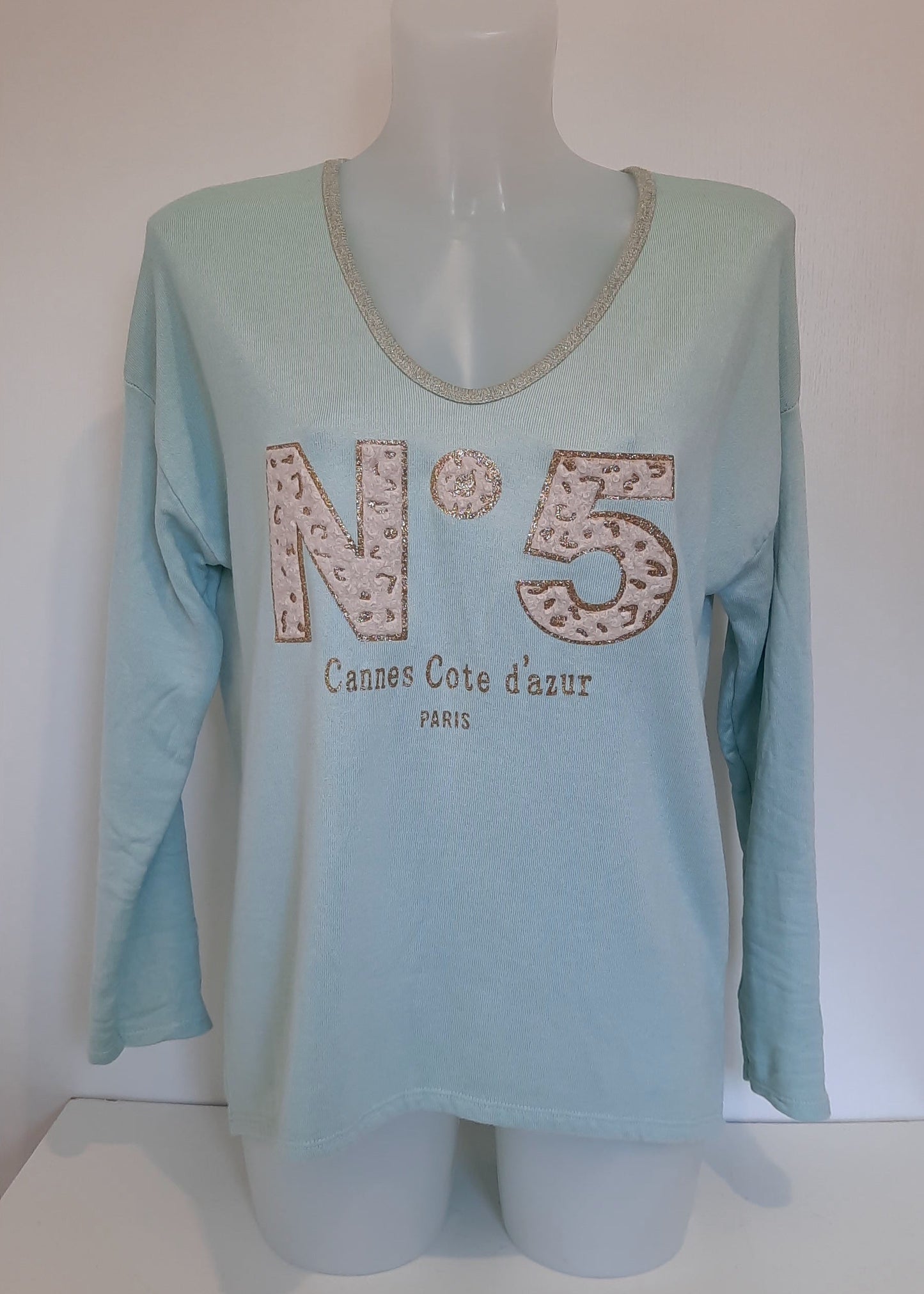 T-shirt vert d'eau à manches longues pour femme, col en V avec bord lurex doré, inscription 'N°5 Cannes Côte d’Azur Paris' en relief léopard et doré. Style casual chic inspiré des tendances parisiennes.