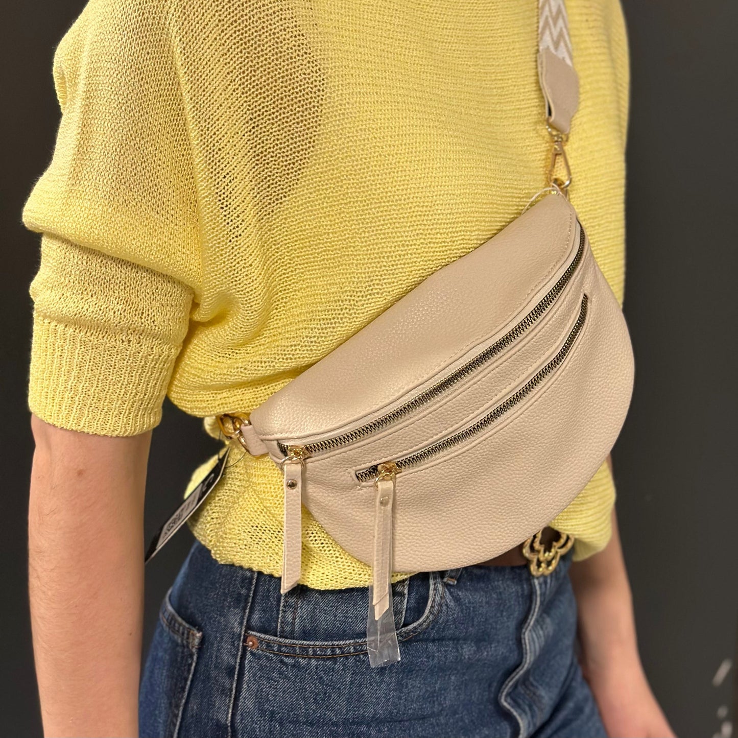 Banane Gallantry beige en simili cuir grainé, avec sangle réglable à motif chevrons, fermeture zippée et poche frontale, idéale pour un look tendance et pratique