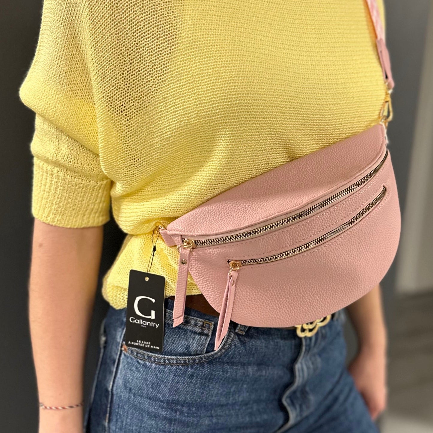 Banane Gallantry rose poudré en simili cuir grainé, avec sangle réglable à motif chevrons, fermeture zippée et poche frontale, idéale pour un look tendance et pratique