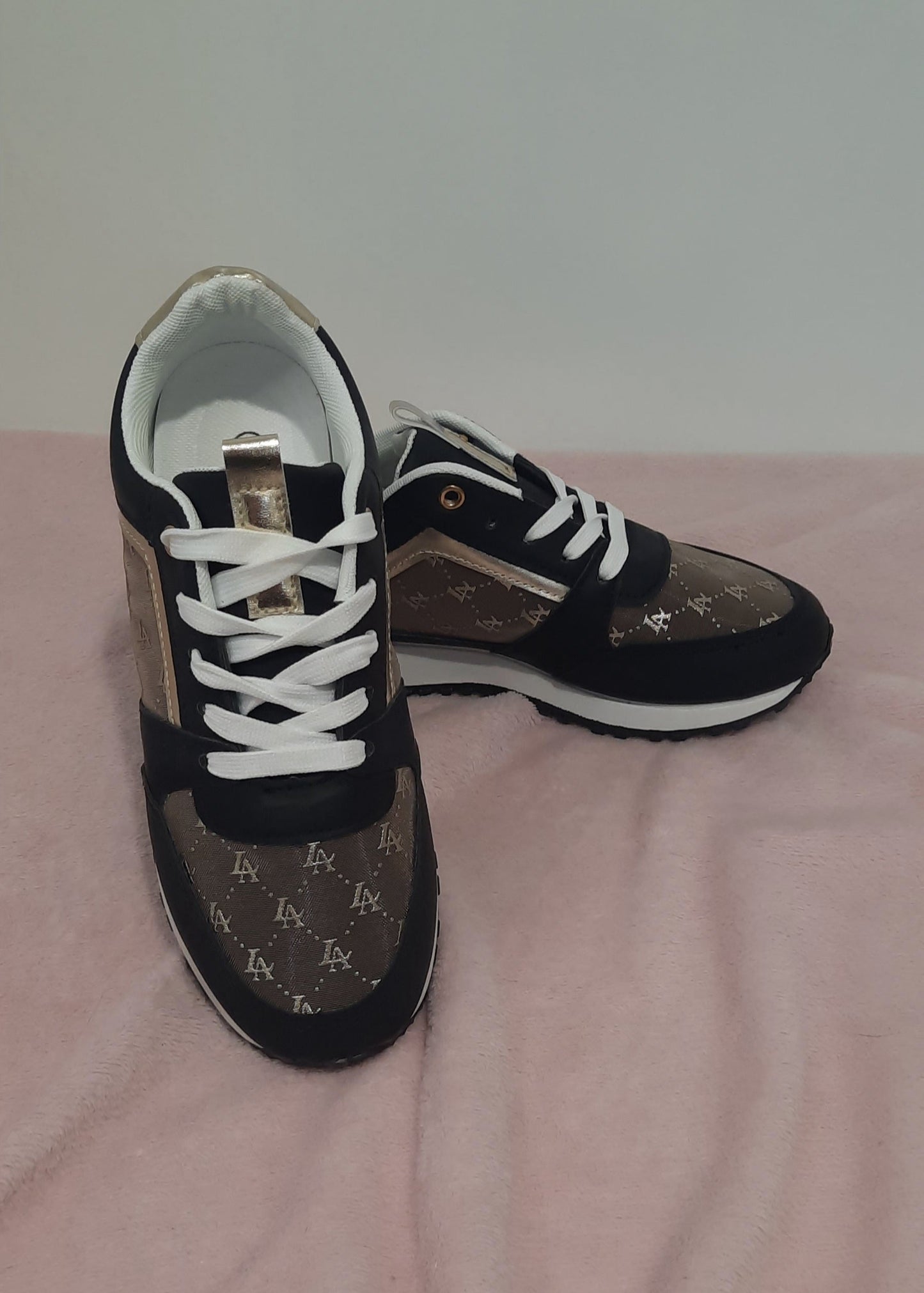 Baskets femme noires et marron avec détails dorés, imprimé monogramme doré, semelle blanche et noire, lacets blancs et œillets dorés. Un modèle chic et urbain – collection Timalya chaussures.