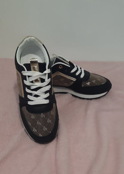 Baskets femme noires et marron avec détails dorés, imprimé monogramme doré, semelle blanche et noire, lacets blancs et œillets dorés. Un modèle chic et urbain – collection Timalya chaussures.
