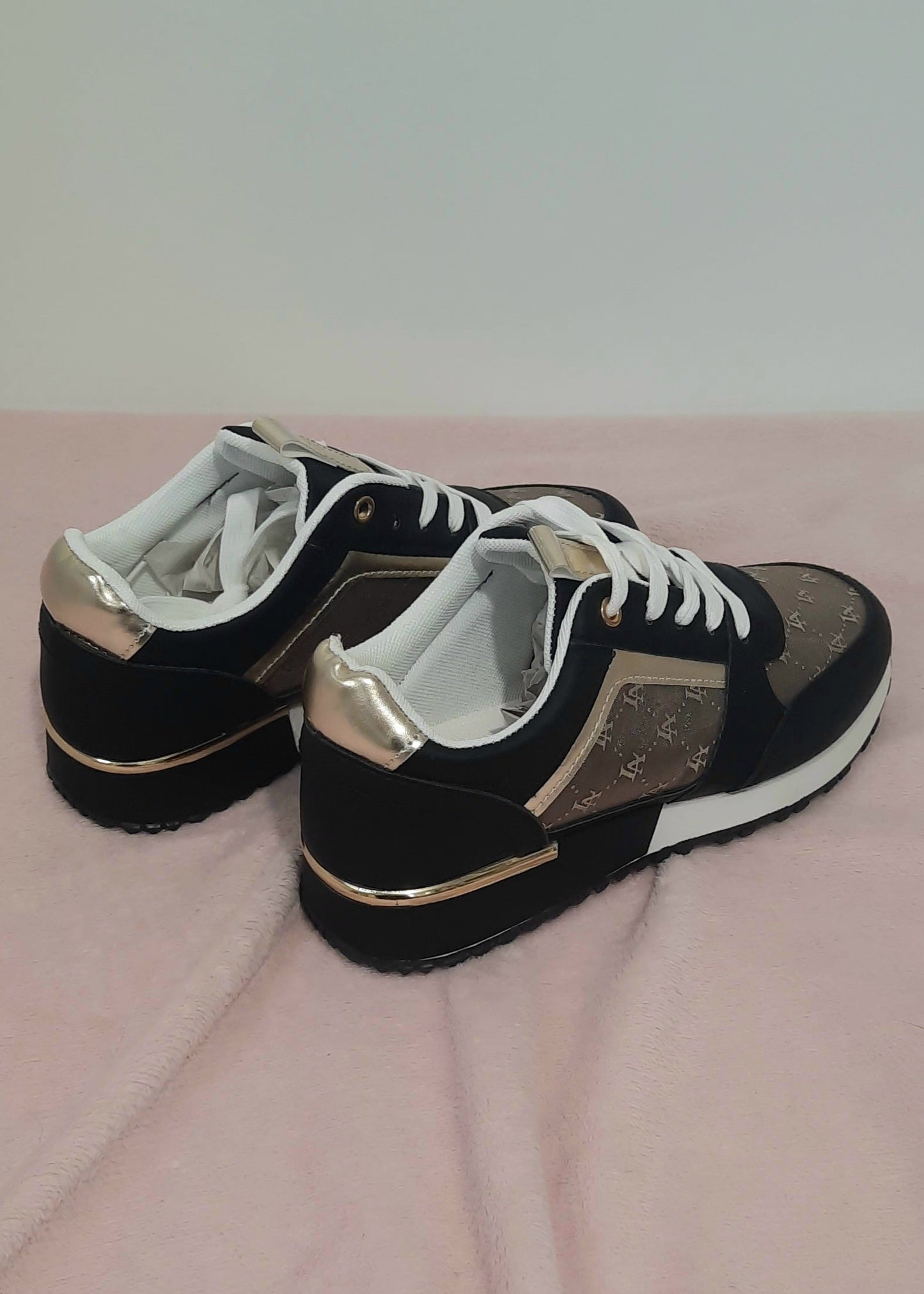 Baskets femme noires et marron avec détails dorés, imprimé monogramme doré, semelle blanche et noire, lacets blancs et œillets dorés. Un modèle chic et urbain – collection Timalya chaussures.