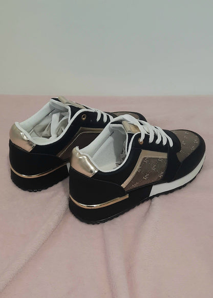 Baskets femme noires et marron avec détails dorés, imprimé monogramme doré, semelle blanche et noire, lacets blancs et œillets dorés. Un modèle chic et urbain – collection Timalya chaussures.