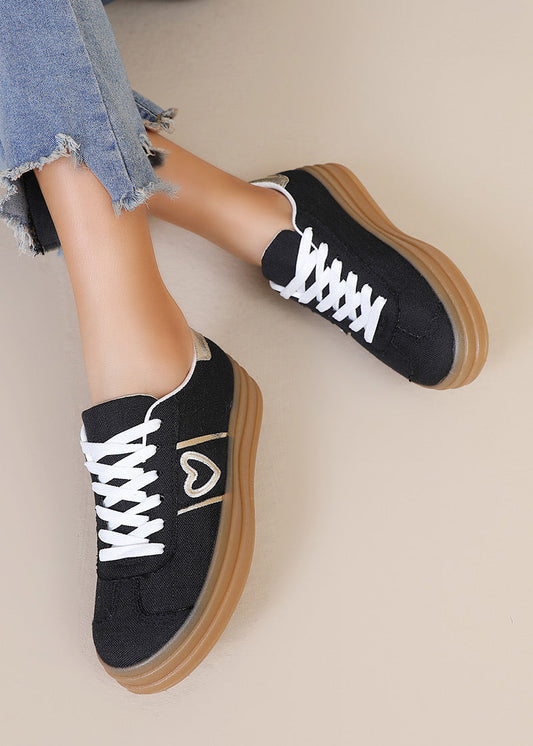 Baskets noires pour femme avec semelle plateforme beige, lacets blancs, cœur doré brodé sur le côté et détail métallisé au talon. Modèle confortable et tendance signé Timalya prêt-à-porter.