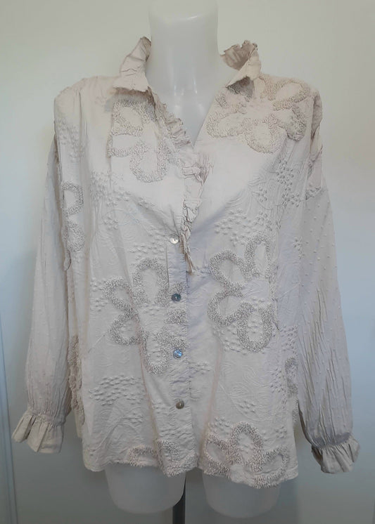 Blouse romantique beige pour femme avec broderies florales en relief et col à volants – manches longues bouffantes et fermeture boutonnée, parfaite pour un look chic et bohème.