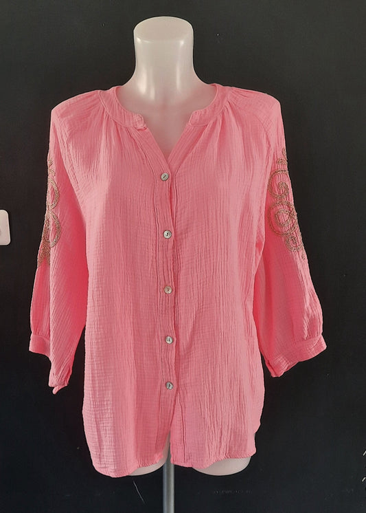Blouse rose en gaze de coton pour femme, manches 3/4 avec broderies dorées sur les bras, encolure tunisienne et boutonnage frontal. Style bohème chic et léger.