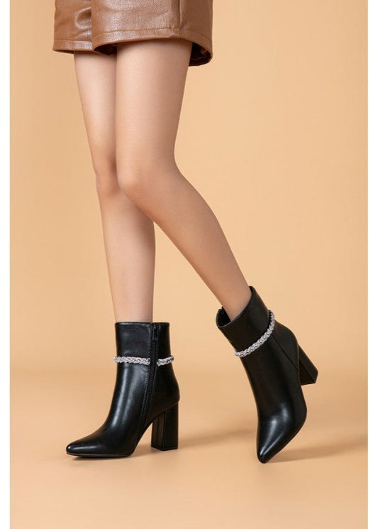 Bottines noires pour femme avec bout pointu, talon carré élégant, fermeture zippée latérale et chaîne brillante autour de la cheville. Un modèle chic et raffiné de la collection Timalya chaussures tendance.