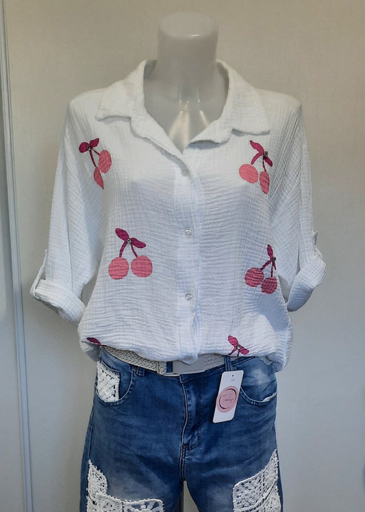 Chemise blanche en gaze de coton pour femme, ornée de broderies cerises roses avec strass – modèle à manches longues retroussables et col classique pour un style estival et ludique.