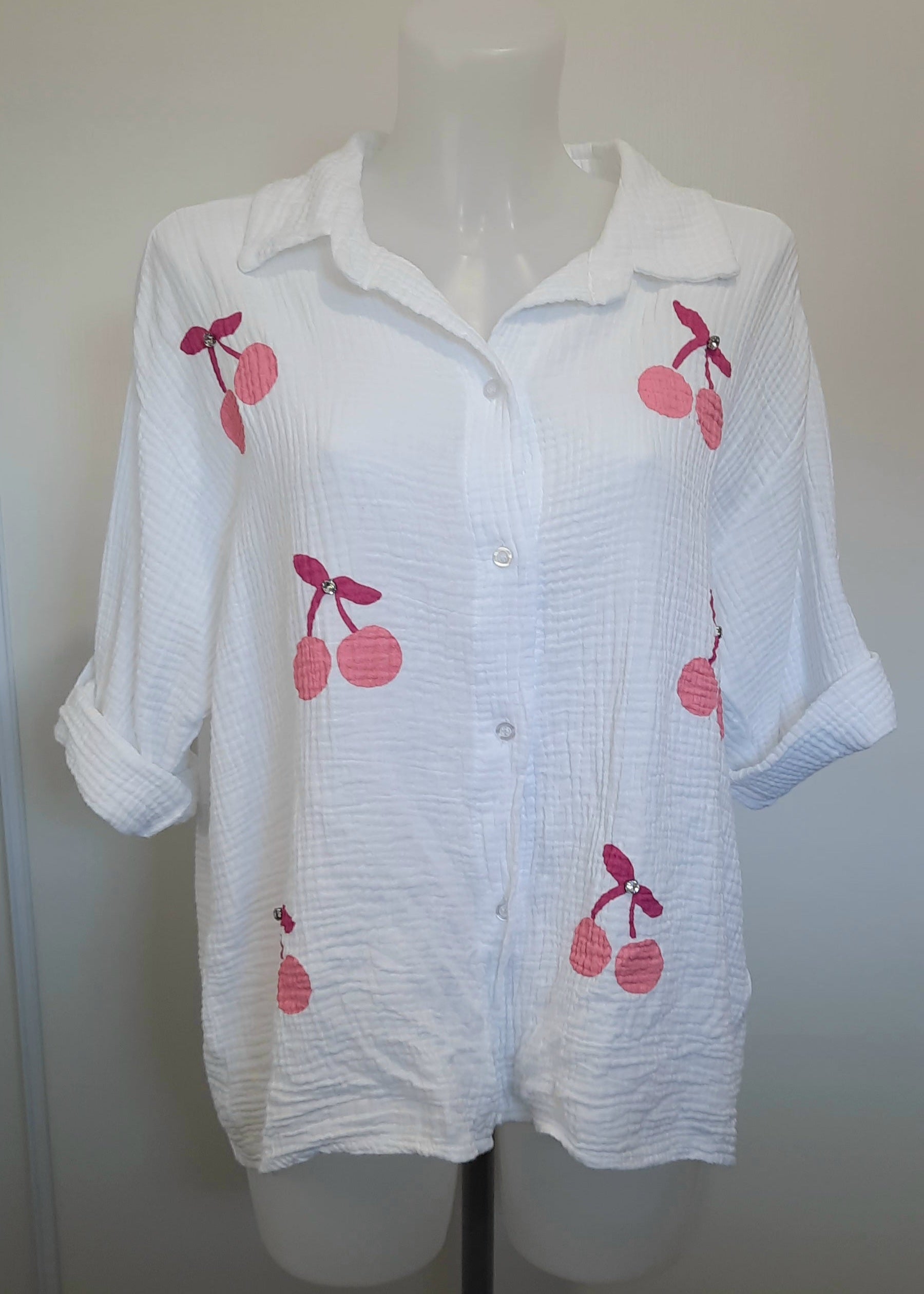 Chemise blanche en gaze de coton pour femme, ornée de broderies cerises roses avec strass – modèle à manches longues retroussables et col classique pour un style estival et ludique.