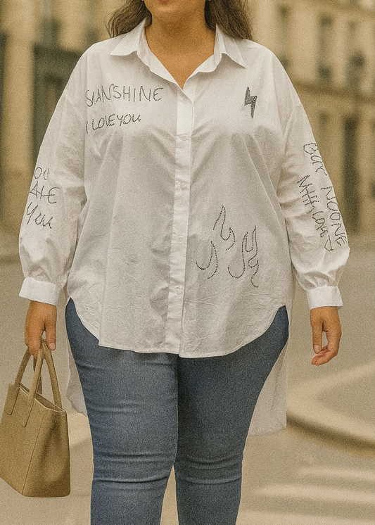 Chemise blanche oversize femme avec inscriptions en strass – design asymétrique et moderne, manches longues bouffantes, idéale pour un look casual chic.