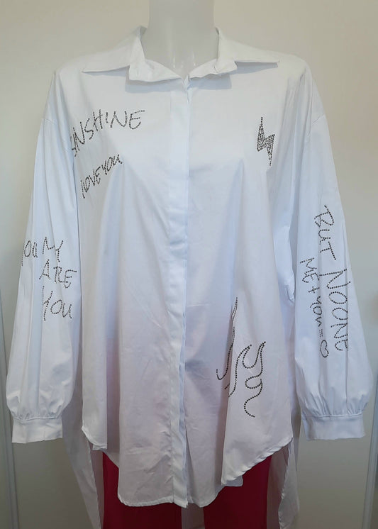 Chemise blanche oversize femme avec inscriptions en strass – design asymétrique et moderne, manches longues bouffantes, idéale pour un look casual chic.