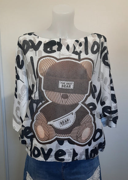 Haut ample blanc à manches 3/4 avec motif nounours marron et inscriptions 'love' en noir, tissu effet mesh léger. Style streetwear décontracté et fun.