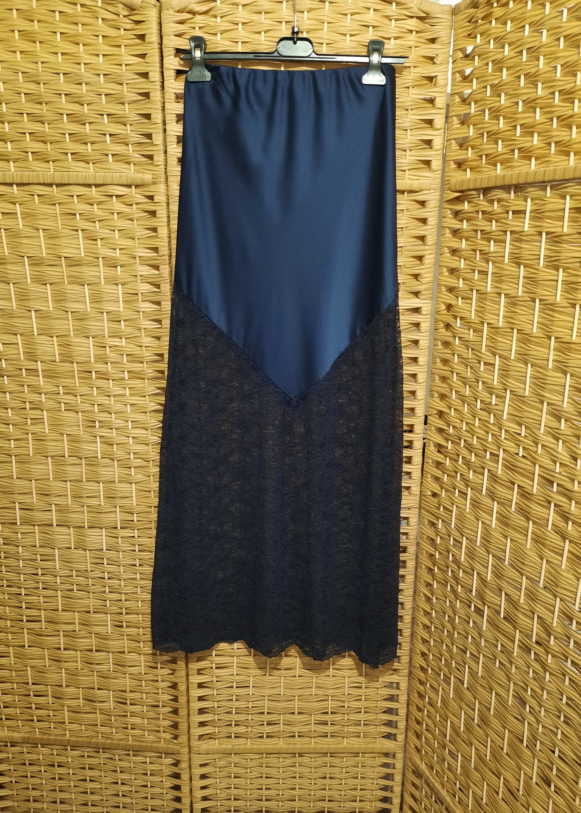 Jupe longue bleu marine en satin avec empiècement asymétrique en dentelle transparente à la base. Coupe droite et élégante, idéale pour une tenue de soirée ou une occasion spéciale.