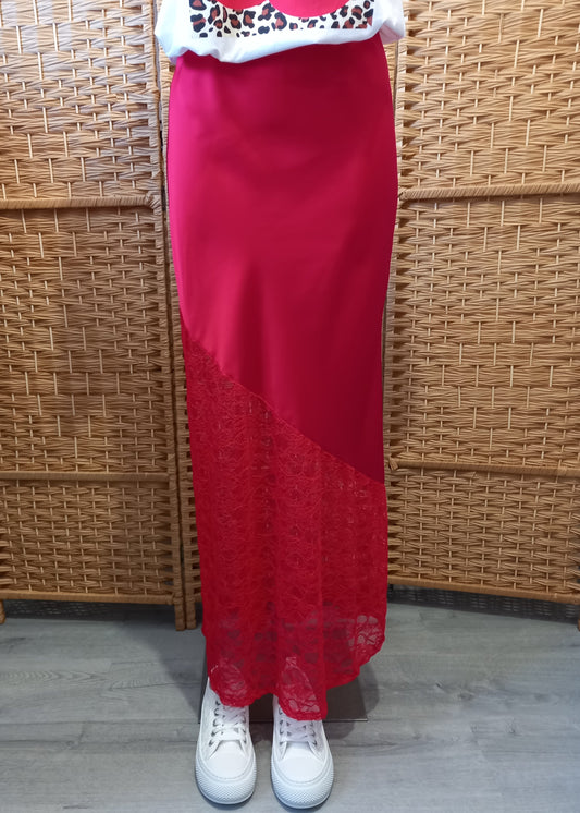 Jupe longue rouge en satin avec empiècement asymétrique en dentelle transparente à la base. Coupe droite et élégante, idéale pour une tenue de soirée ou une occasion spéciale.