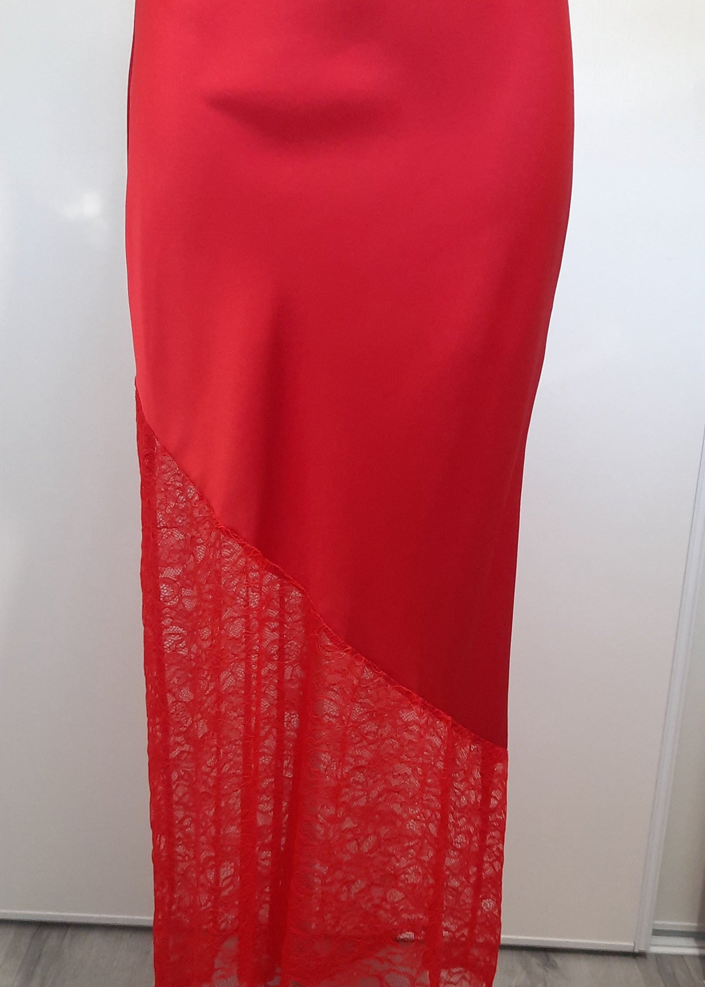 Jupe longue rouge en satin avec empiècement asymétrique en dentelle transparente à la base. Coupe droite et élégante, idéale pour une tenue de soirée ou une occasion spéciale.