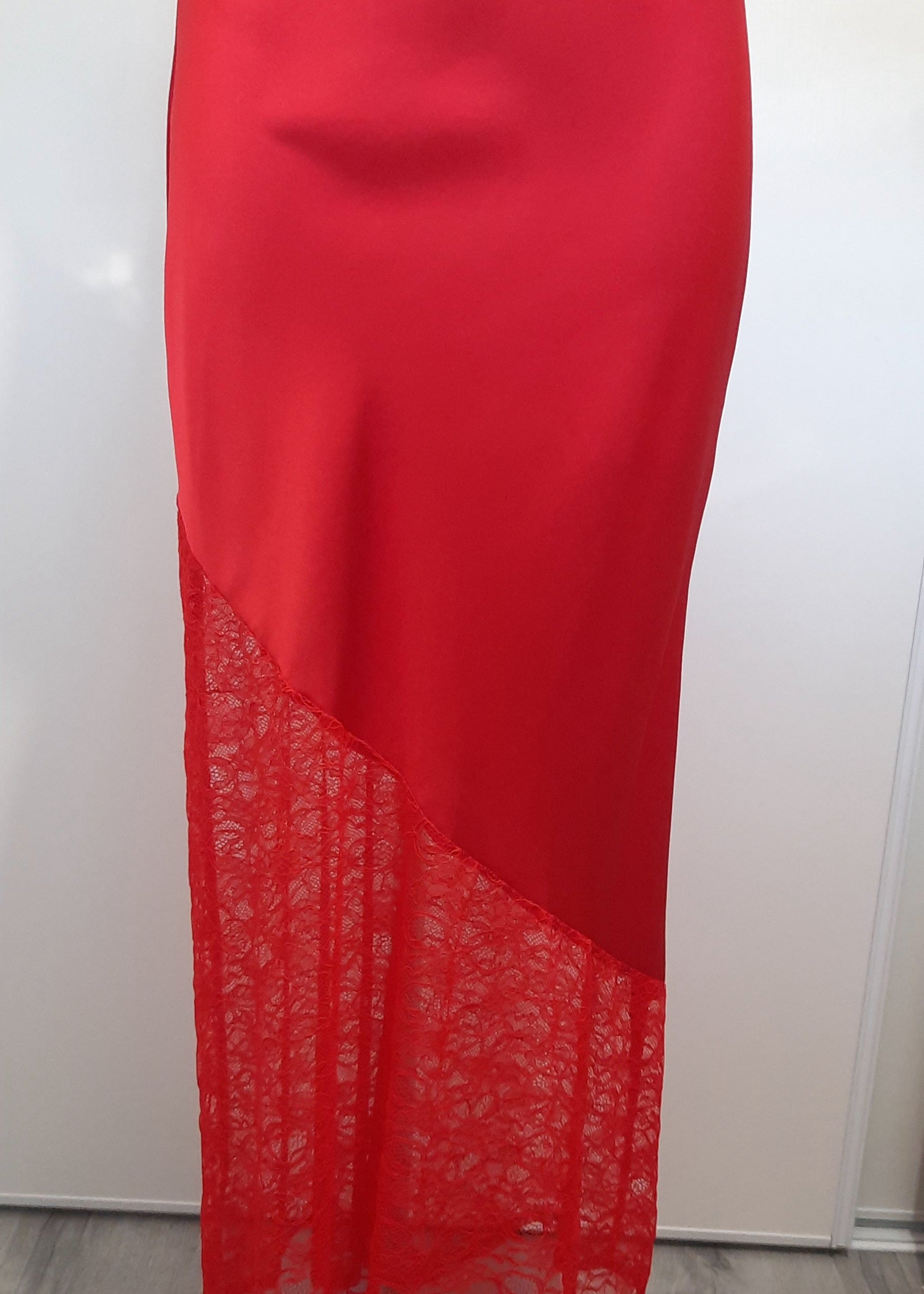 Jupe longue rouge en satin avec empiècement asymétrique en dentelle transparente à la base. Coupe droite et élégante, idéale pour une tenue de soirée ou une occasion spéciale.