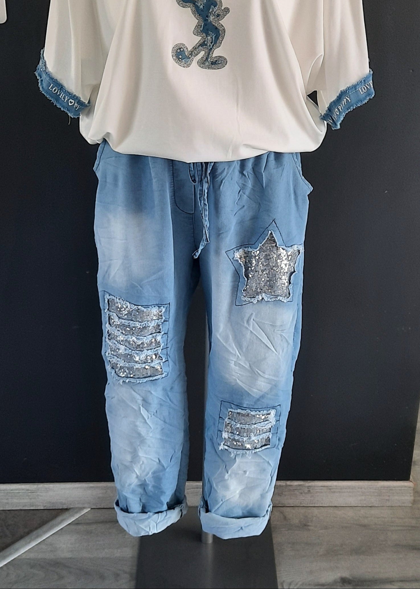 Pantalon jogger bleu clair pour femme, coupe décontractée avec taille élastique et lien à nouer, décoré de patchs à sequins argentés dont une étoile brillante. Style casual tendance avec une touche d’originalité.