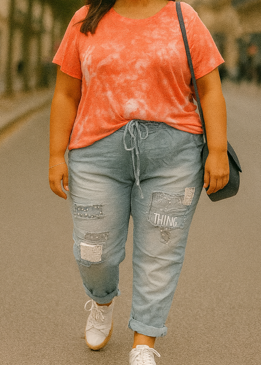 Pantalon jogging bleu clair pour femme, coupe décontractée avec taille élastique et lien de serrage, décoré de patchs brodés, clous et sequins argentés. Style streetwear tendance et confortable.