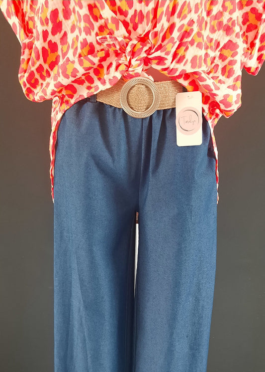 Pantalon large en denim léger clair, coupe fluide style palazzo, ceinture élastique tressée beige avec boucle ronde dorée. Look décontracté chic, parfait pour le printemps et l’été.