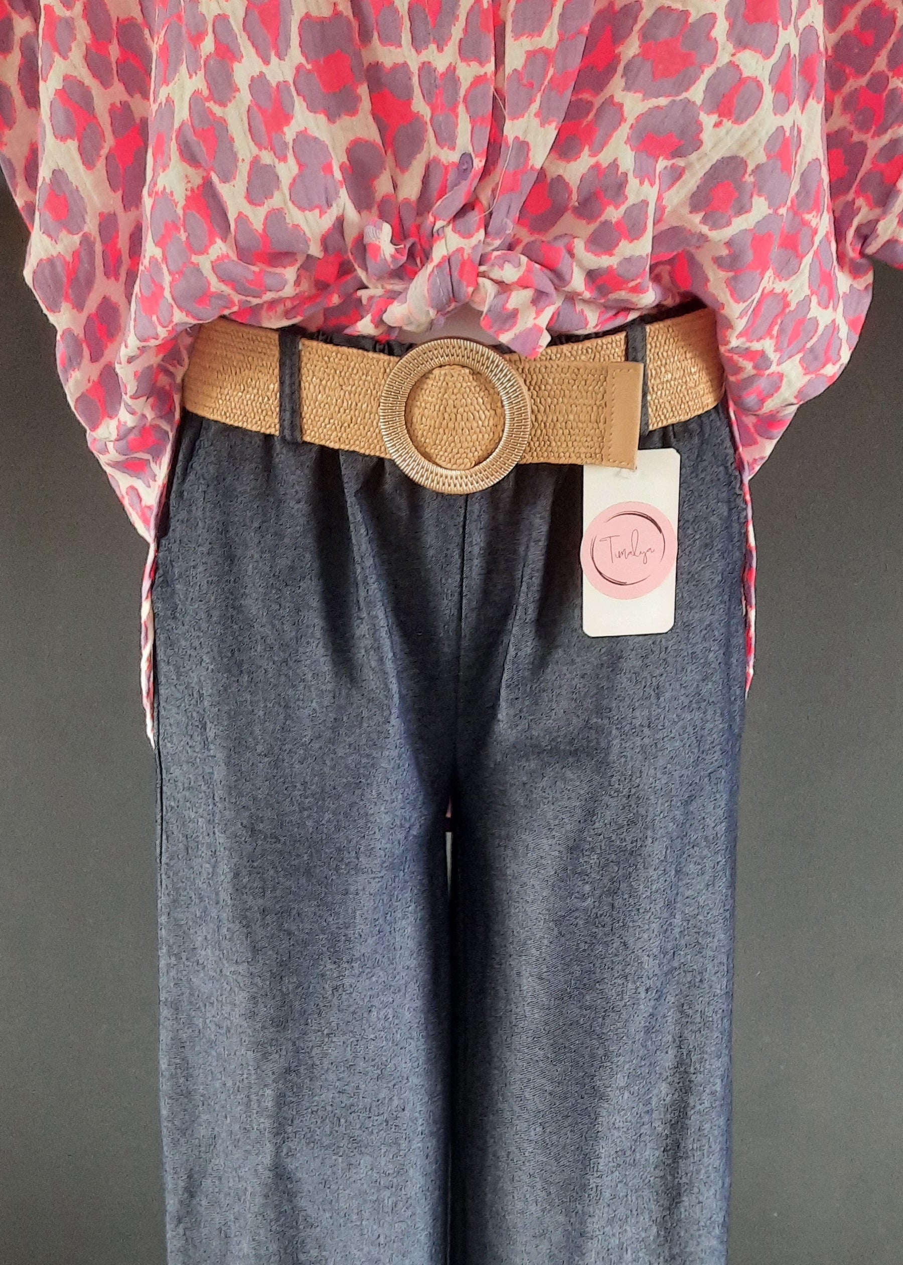Pantalon large en denim léger foncé, coupe fluide style palazzo, ceinture élastique tressée beige avec boucle ronde dorée. Look décontracté chic, parfait pour le printemps et l’été.