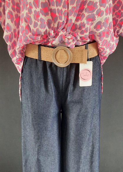 Pantalon large en denim léger foncé, coupe fluide style palazzo, ceinture élastique tressée beige avec boucle ronde dorée. Look décontracté chic, parfait pour le printemps et l’été.