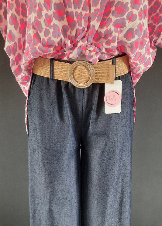 Pantalon large en denim léger foncé, coupe fluide style palazzo, ceinture élastique tressée beige avec boucle ronde dorée. Look décontracté chic, parfait pour le printemps et l’été.