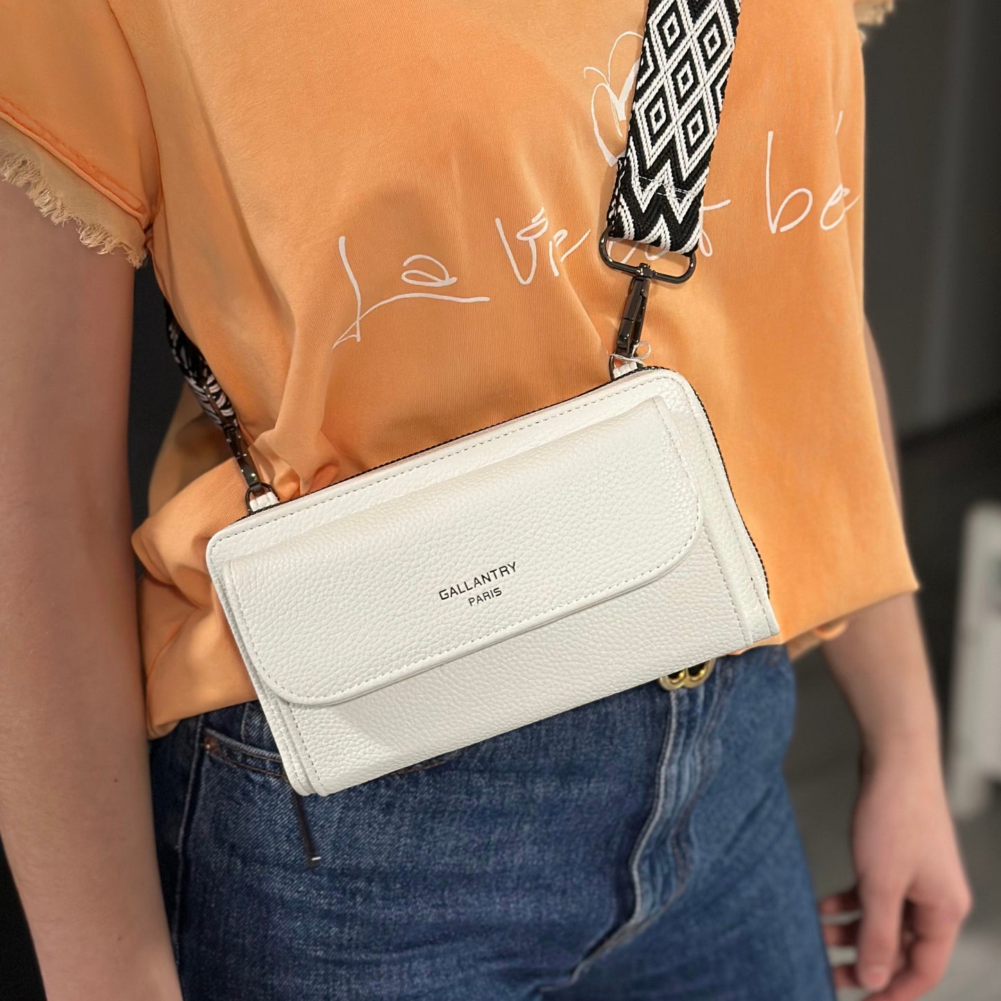 Portefeuille à bandoulière Gallantry en simili cuir blanc, avec grande poche frontale et sangle fantaisie à motif chevrons, pratique et tendance pour femme