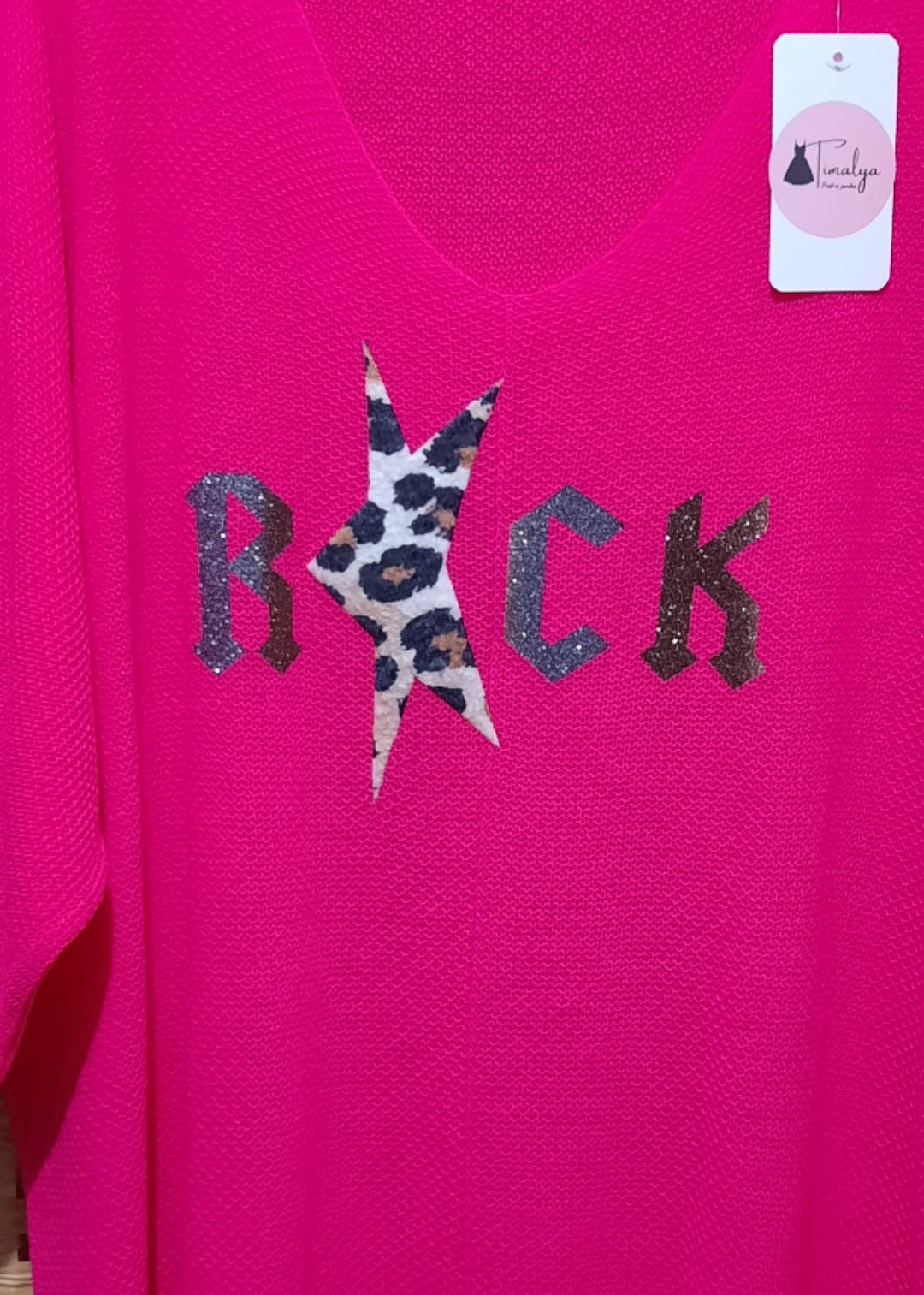 Pull femme fuchsia style rock, col V et manches 3/4 en maille douce oversize, motif “ROCK” avec étoile léopard pailletée sur le devant, idéal avec un pantalon blanc.