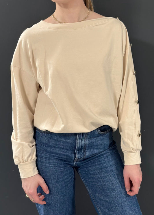 Sweat beige clair pour femme, coupe droite avec boutons dorés décoratifs sur l’épaule et le long de la manche. Style casual chic avec une touche d’originalité.