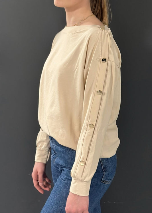 Sweat beige clair pour femme, coupe droite avec boutons dorés décoratifs sur l’épaule et le long de la manche. Style casual chic avec une touche d’originalité.