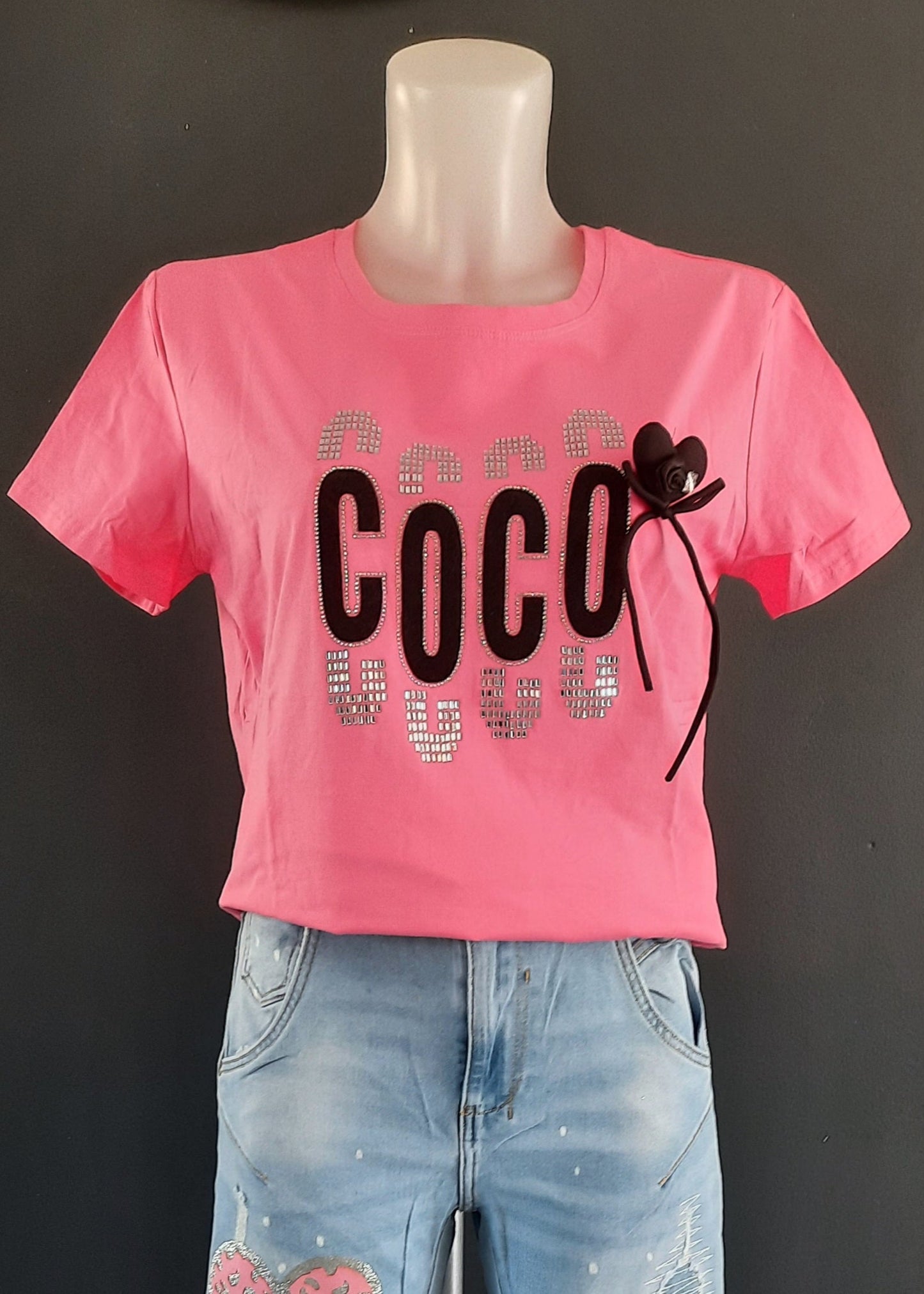 T-shirt fuchsia ajusté “COCO” avec strass argentés et nœud cœur noir amovible, col rond, 95 % coton 5 % élasthanne, tailles S/M (36–38) et M/L (38–40), longueur environ 61–62 cm, style urbain chic, fabriqué en Chine
