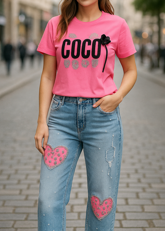 T-shirt fuchsia ajusté “COCO” avec strass argentés et nœud cœur noir amovible, col rond, 95 % coton 5 % élasthanne, tailles S/M (36–38) et M/L (38–40), longueur environ 61–62 cm, style urbain chic, fabriqué en Chine