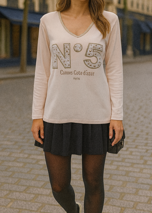 T-shirt beige à manches longues pour femme, col en V avec bord lurex doré, inscription 'N°5 Cannes Côte d’Azur Paris' en relief léopard et doré. Style casual chic inspiré des tendances parisiennes.