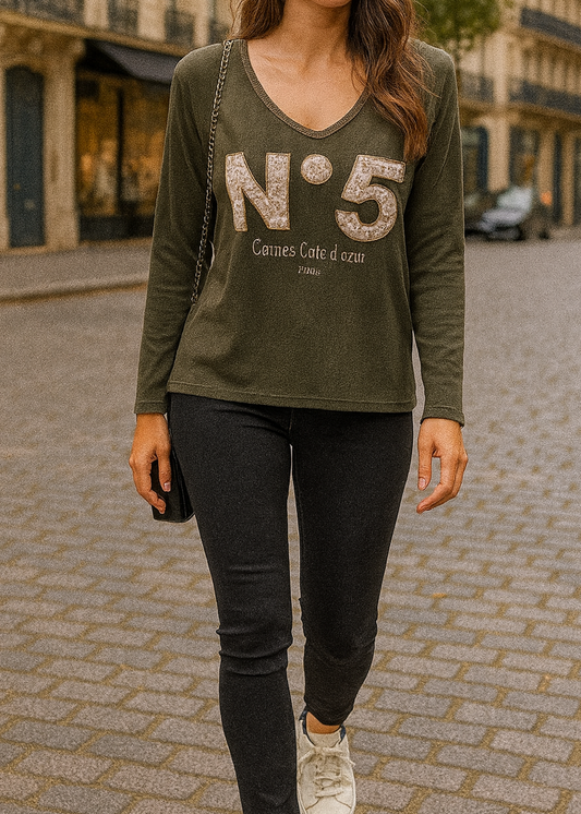 T-shirt kaki à manches longues pour femme, col en V avec bord lurex doré, inscription 'N°5 Cannes Côte d’Azur Paris' en relief léopard et doré. Style casual chic inspiré des tendances parisiennes.
