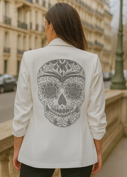 Veste tailleur femme blanche avec coupe droite, manches 3/4 froncées, poches à rabat décoratives et grand motif tête de mort mexicaine en strass noirs dans le dos. Un blazer original et stylé signé Timalya prêt-à-porter féminin.