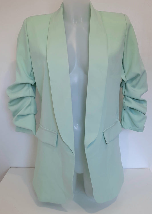Veste tailleur pour femme en tissu fluide vert d’eau, coupe droite avec manches 3/4 froncées, poches à rabat décoratives et col élégant, idéale pour un look tendance, frais et féminin – modèle Timalya prêt-à-porter.