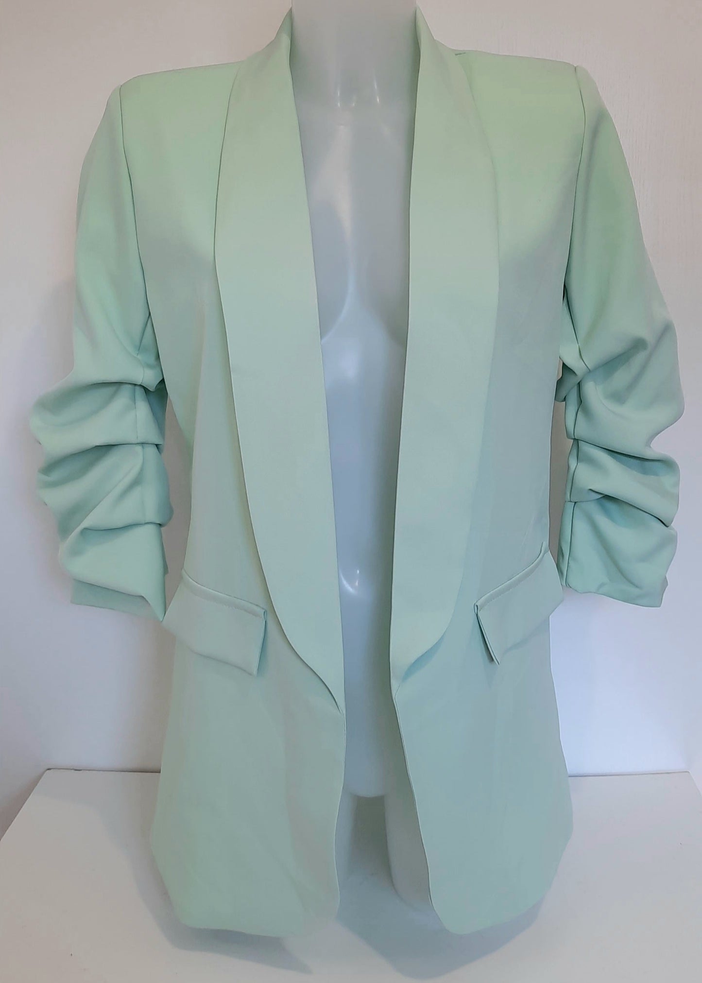 Veste tailleur pour femme en tissu fluide vert d’eau, coupe droite avec manches 3/4 froncées, poches à rabat décoratives et col élégant, idéale pour un look tendance, frais et féminin – modèle Timalya prêt-à-porter.